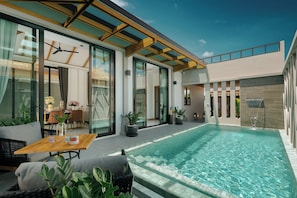 A modern pool area with a glass-enclosed patio, outdoor furniture, and potted plants. - Rawayana Villas (Rawai)