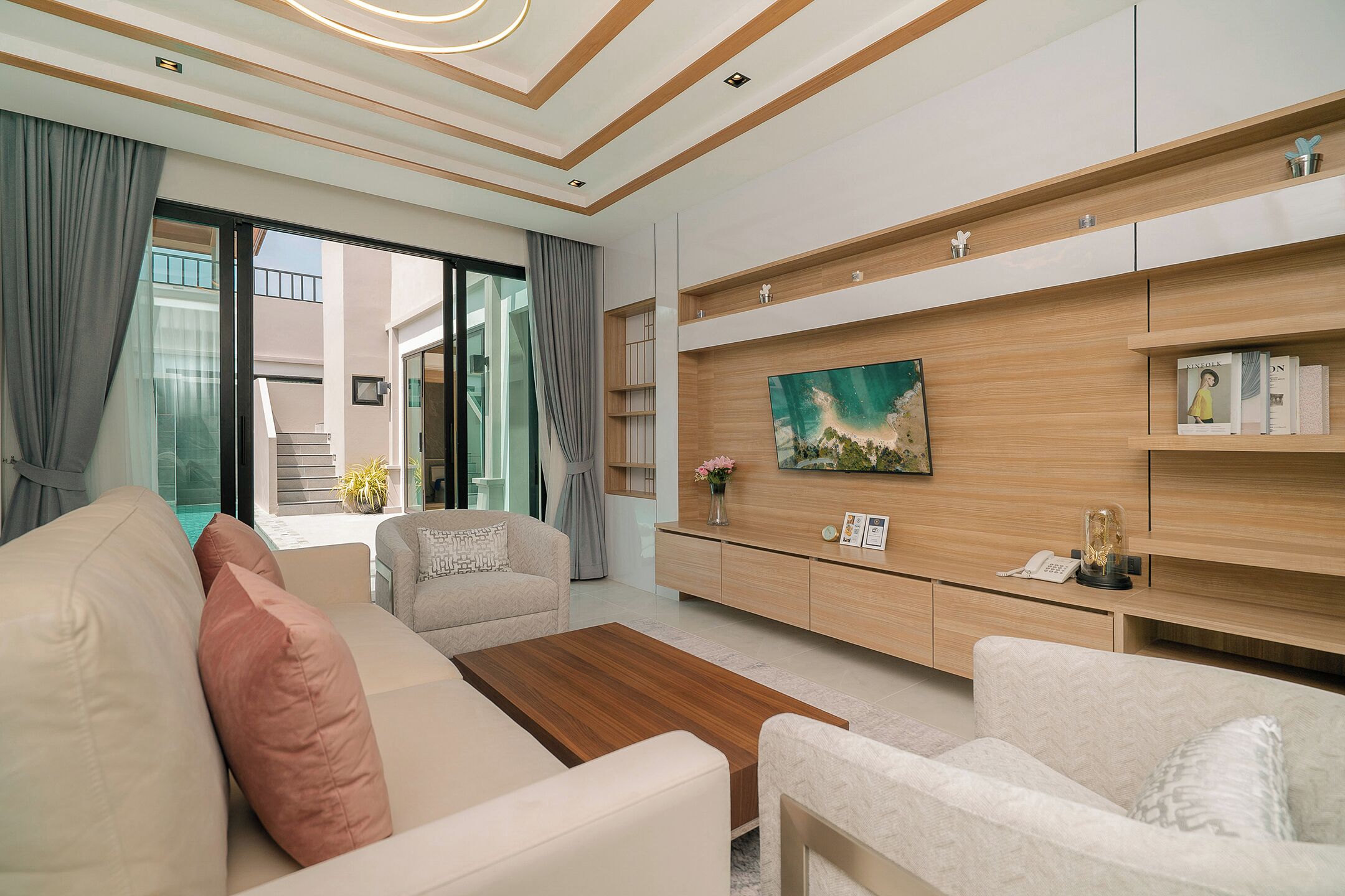 A modern living room with a sofa, armchairs, a coffee table, a TV, and a bookshelf.