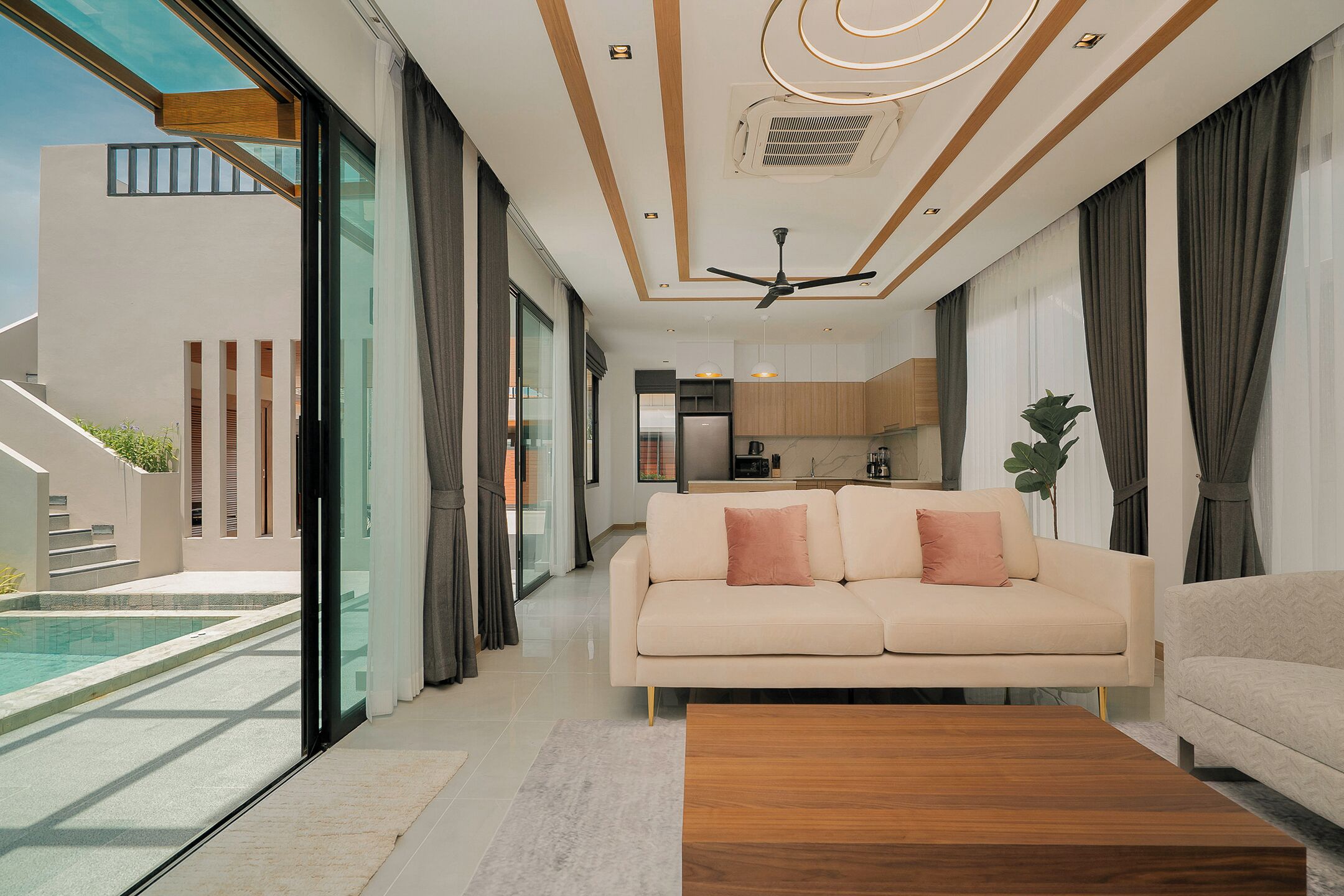 A modern living room with a sofa, a coffee table, and a view of a swimming pool.