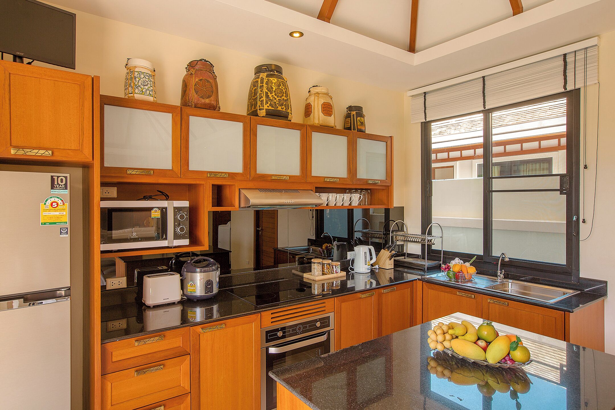 A kitchen with wooden cabinets, a microwave, a stove, and a fruit bowl on the counter.