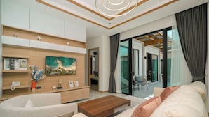 A modern living room with a sofa, coffee table, and a painting on the wall. - Rawayana Villas (Rawai)
