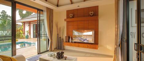 A modern living room with a large TV, a pool view, and a sliding glass door.