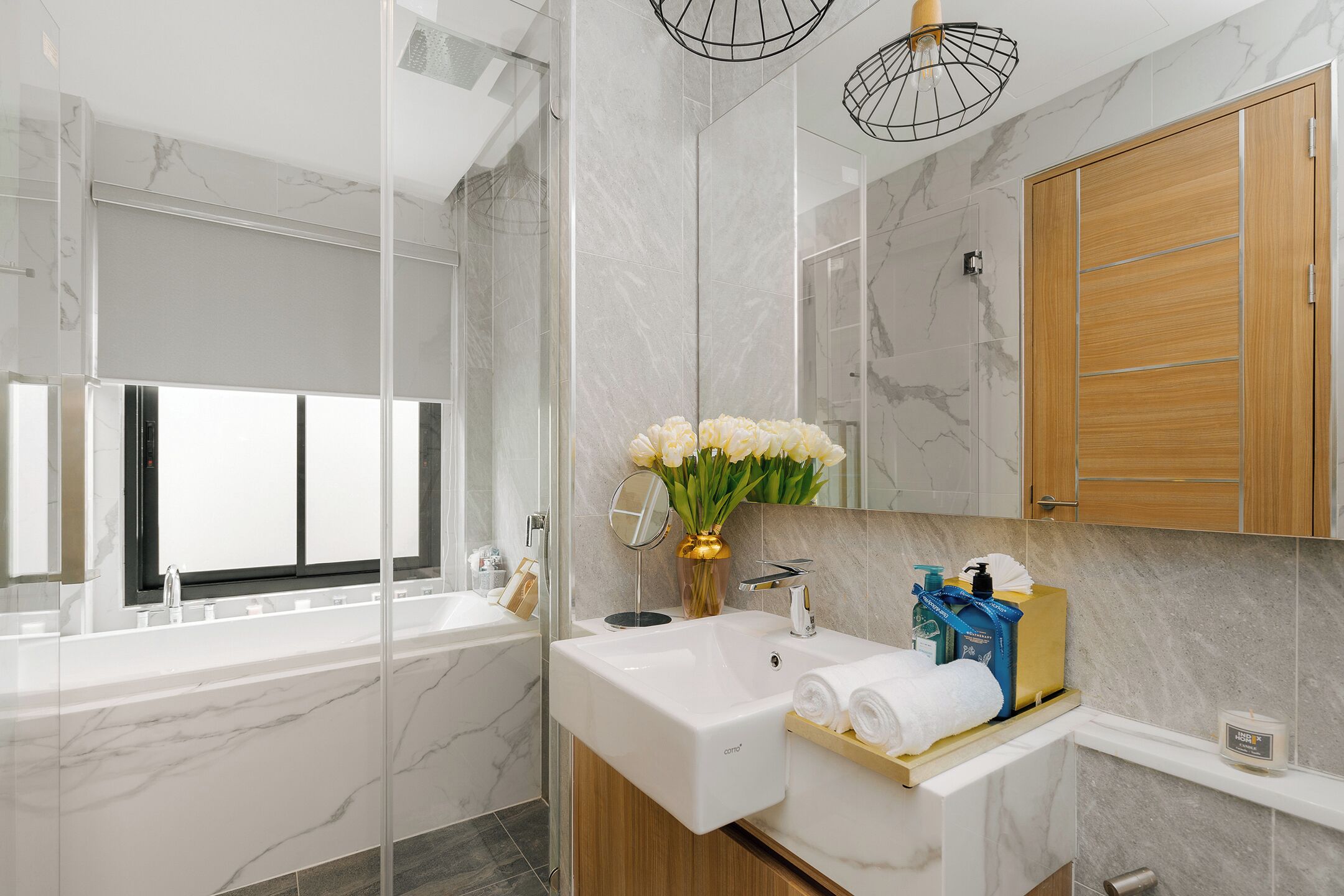 A modern bathroom with a marble sink, a glass shower enclosure, a wooden vanity, and a large mirror.
