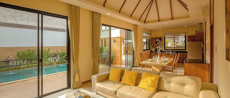 Uma sala de estar espaçosa com um sofá grande, uma mesa de centro e vista para uma piscina.