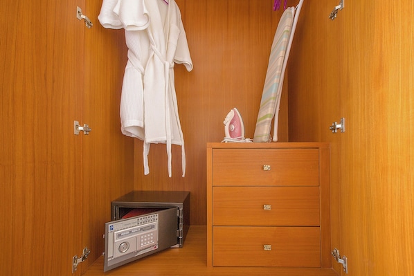 Une armoire en bois avec une radio numérique, un peignoir blanc et une serviette suspendue.