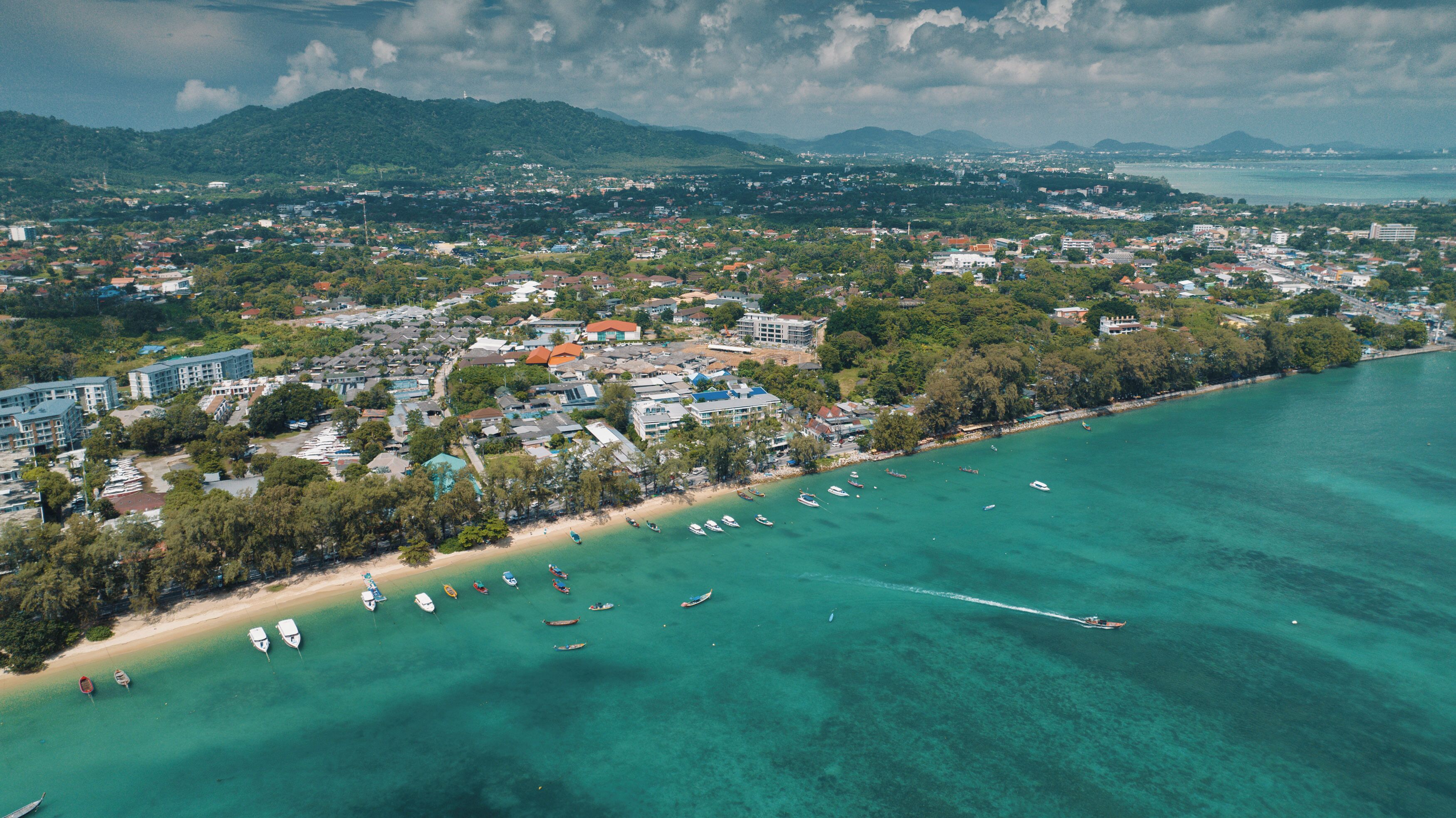 An aerial view of a coastal town with a beach, boats, and buildings.