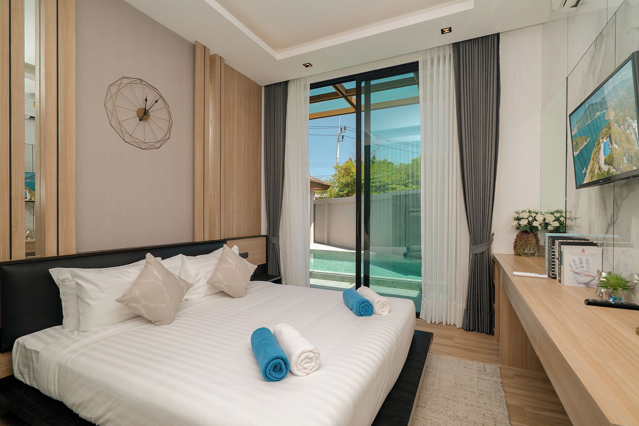 Habitación de hotel con cama, escritorio, televisión y vista a una piscina.
