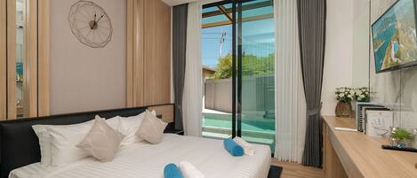 Habitación de hotel con cama, escritorio, televisión y vista a una piscina.