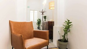 A hallway with a brown leather chair, a floor lamp, and potted plants. - RM4 Chambre en étage - Côté Ville (Sliema)