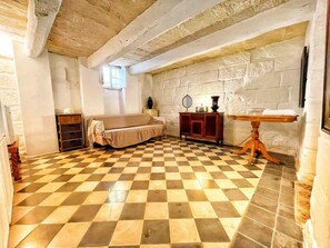 A room with a checkered floor, a sofa, a wooden cabinet, and a table with a mirror.