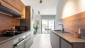 A modern kitchen with a microwave, stove, and oven, a sink, and a view of the outside. - FL2 Sliema Cozy 1BR Getaway with Balcony (Sliema)