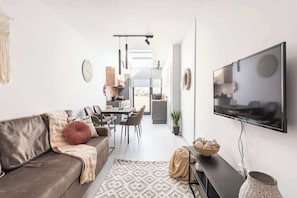 A modern living room with a sofa, TV, and dining area.
