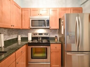 Una cocina con armarios de madera, un refrigerador de acero inoxidable, un microondas y un horno.