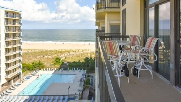 A hotel balcony with a view of the beach and ocean. - Spacious 2 BR 2 Bath Ocean Front building overlooking Pool (Ocean City)