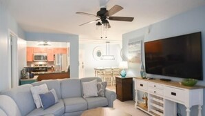 A living room with a sofa, coffee table, TV stand, and a ceiling fan. - Spacious 2 BR 2 Bath Ocean Front building overlooking Pool (Ocean City)