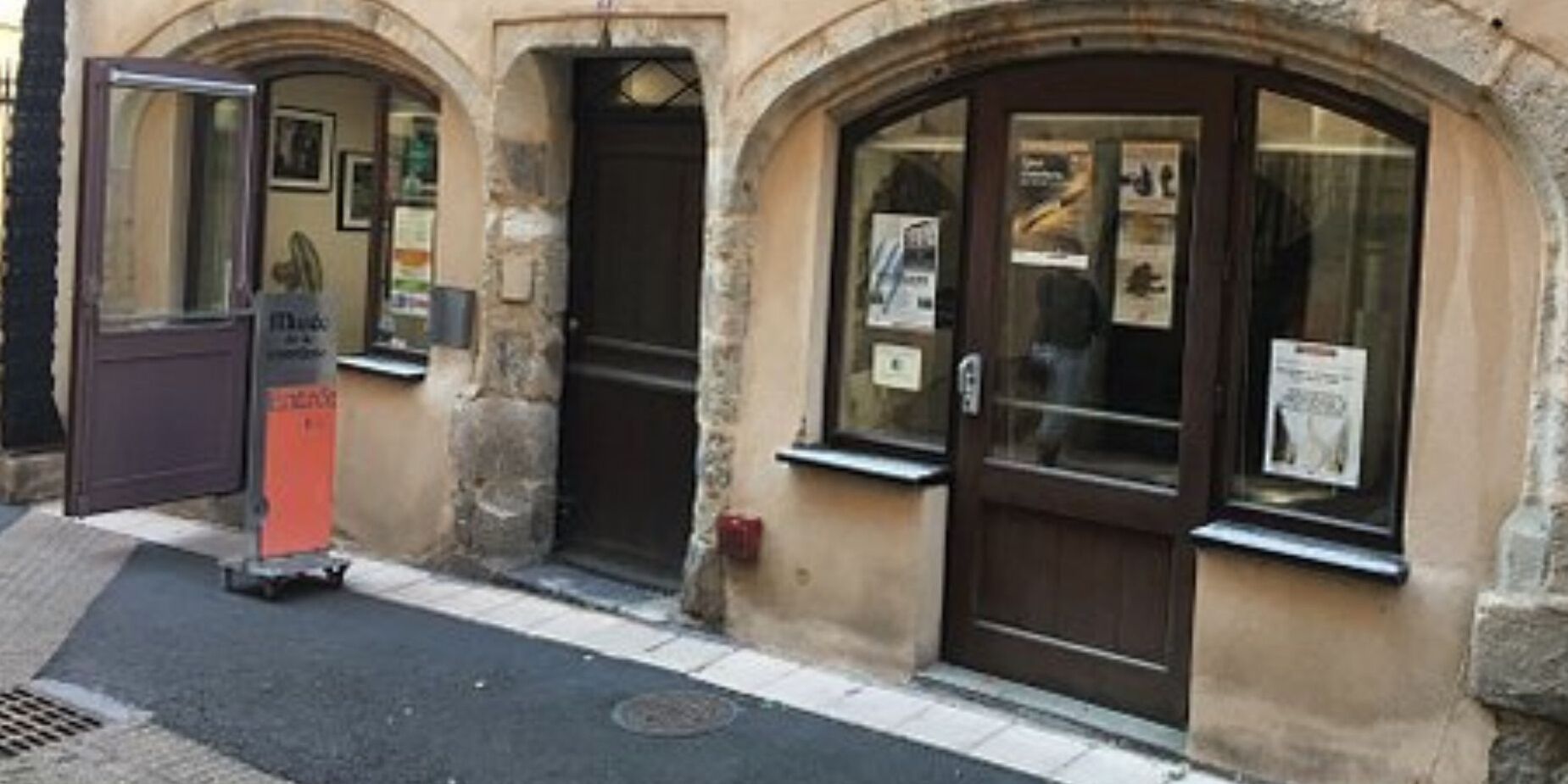 A building with three arched doorways, each with a poster on the wall.