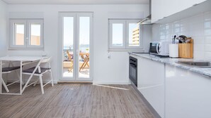 A modern kitchen with white cabinets, a built-in oven, and a dining area with a table and chairs. - Designer Flats in Lapa by LovelyStay (Lisbon)