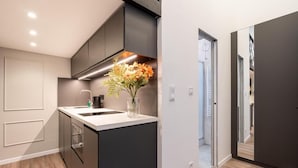 Une cuisine moderne avec des meubles de couleur sombre, un plan de travail blanc et un vase rempli de fleurs.