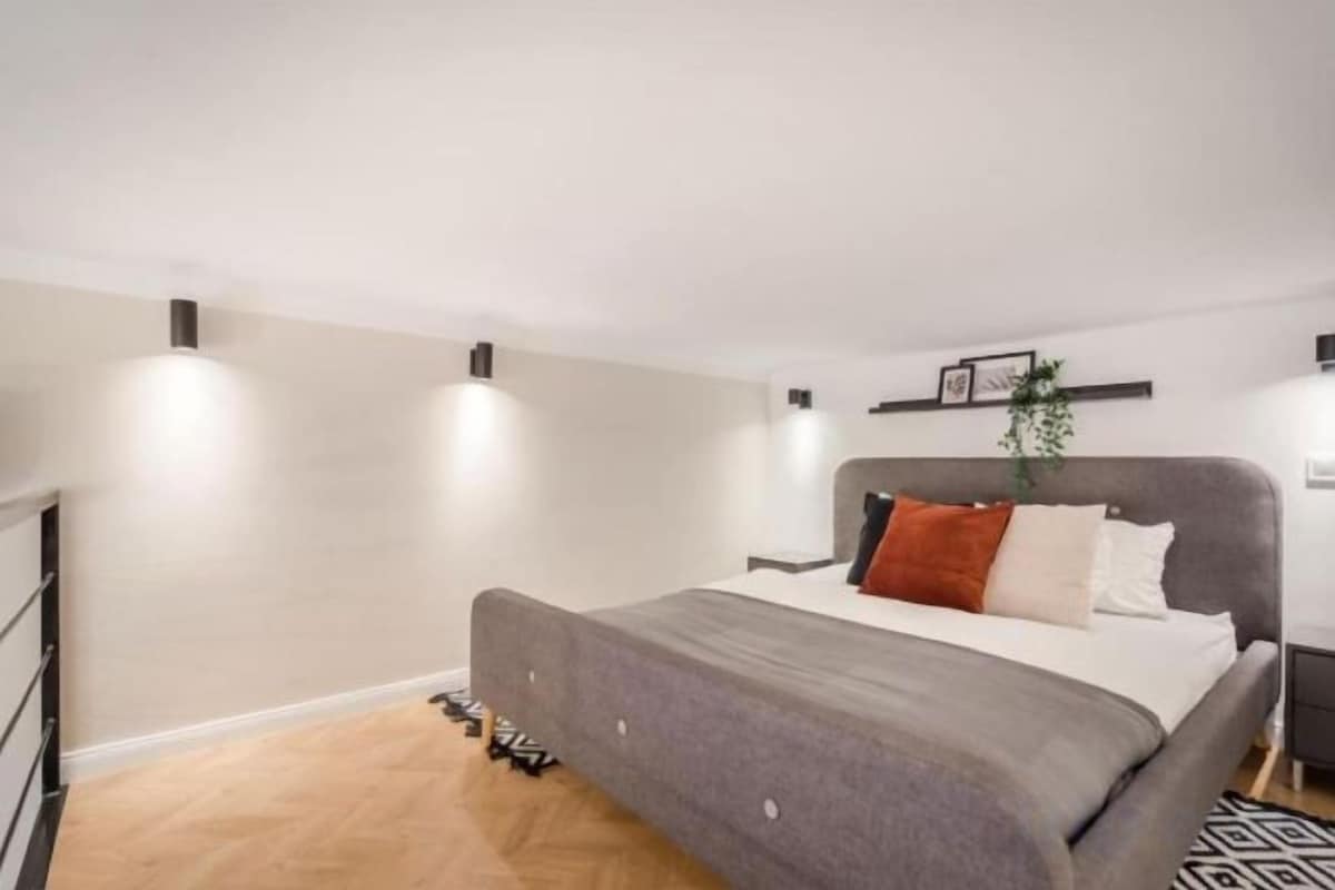 Une chambre à coucher comprenant un lit, une table de chevet, une étagère murale et une plante.