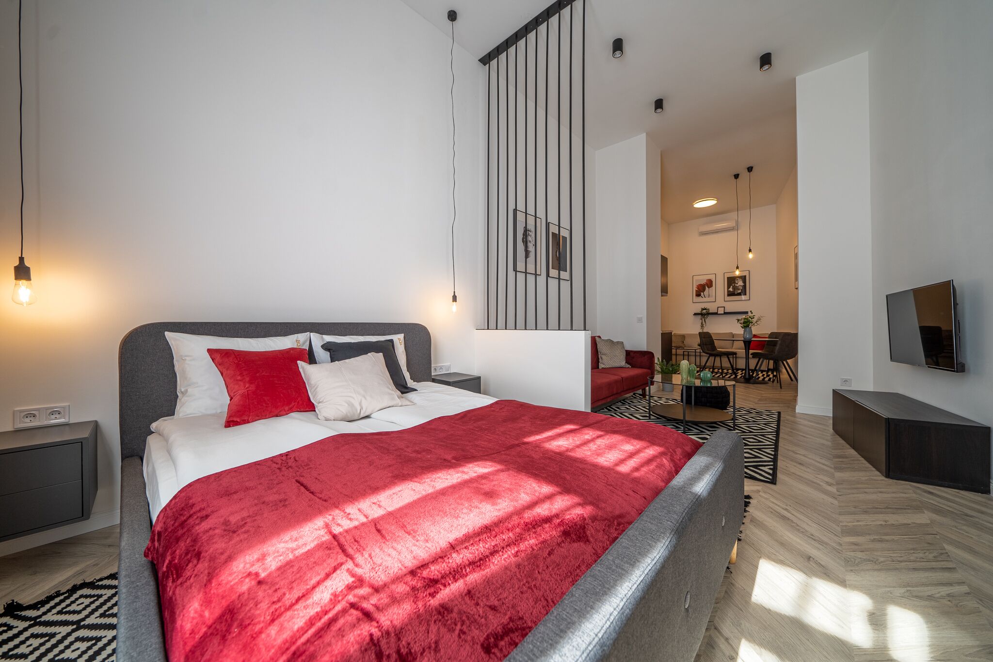 Ein modernes Schlafzimmer mit einem großen Bett, einem Fernseher und einem Essbereich im Hintergrund.