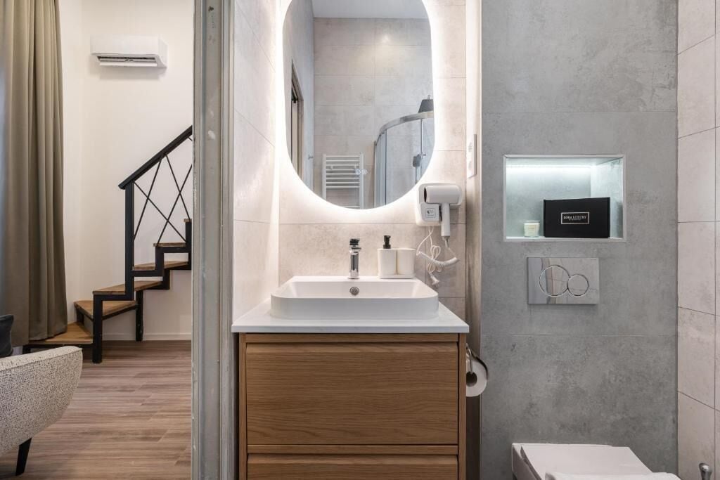 Un baño moderno con un lavamanos independiente, un espejo y un perchero para toallas.