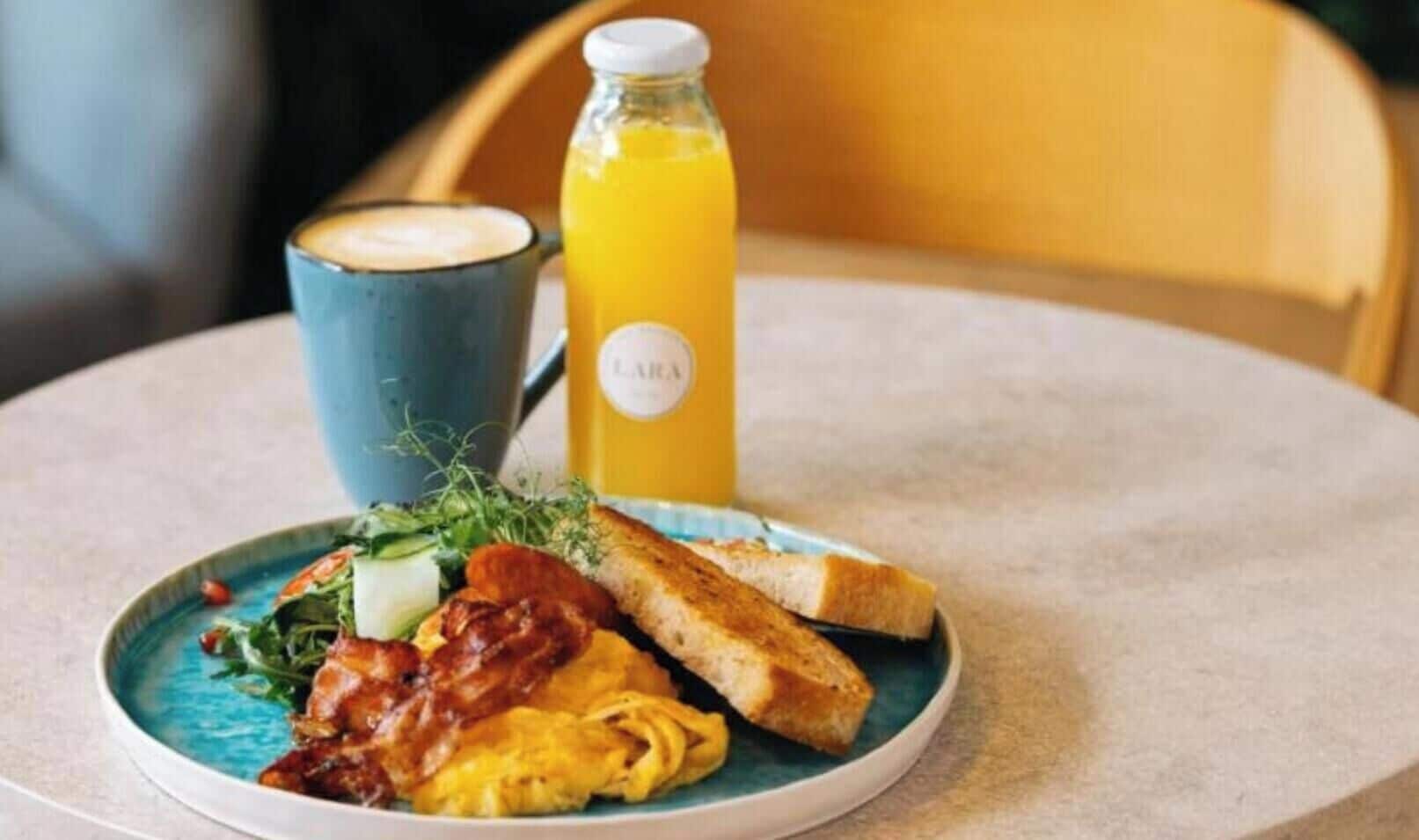 A breakfast plate with toast, scrambled eggs, bacon, and a cup of coffee.