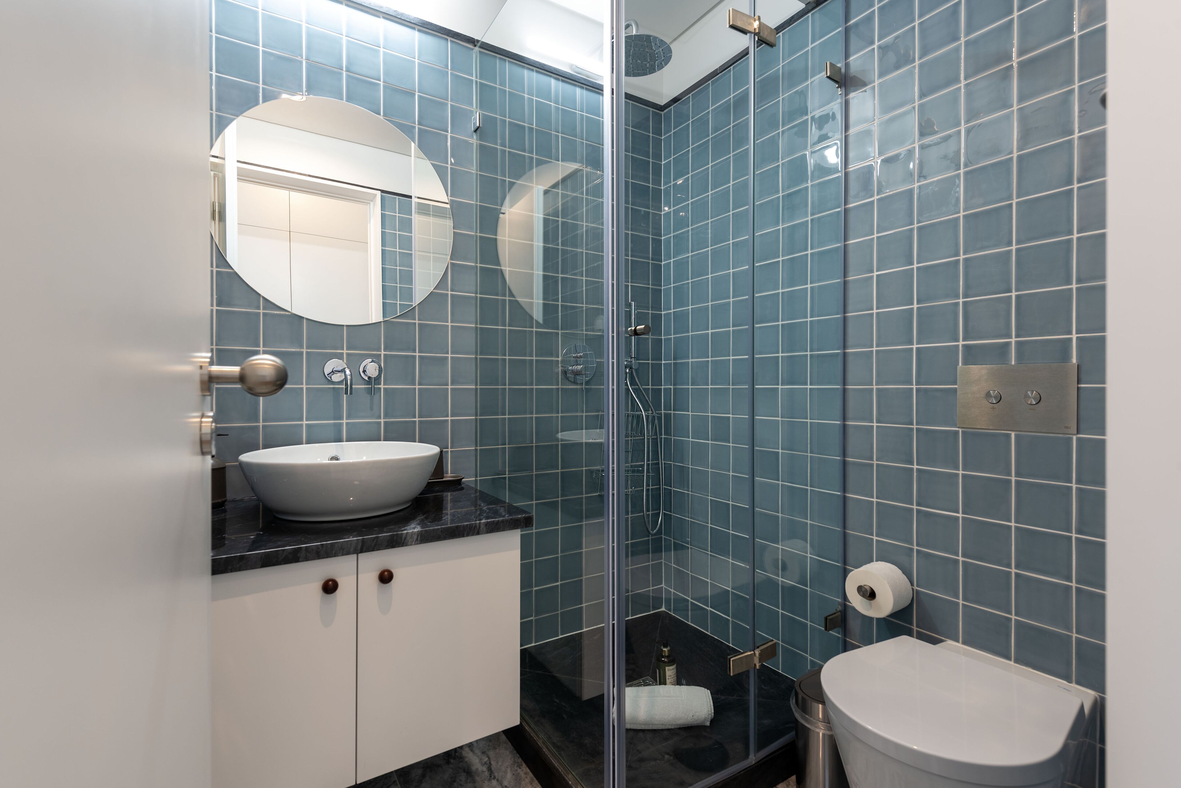 A bathroom with a white sink, a mirror, a toilet, and a glass-enclosed shower area.