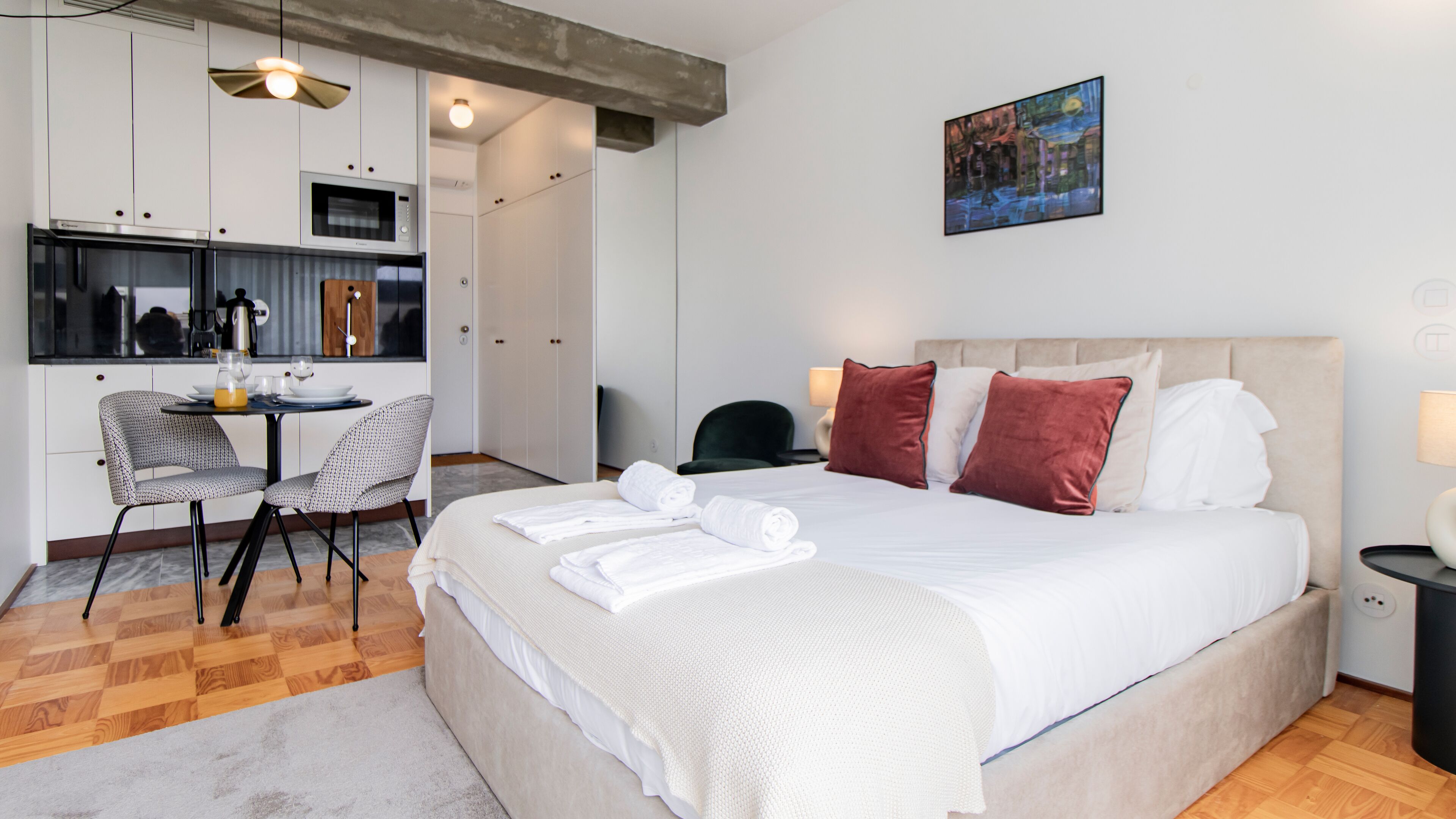 Una habitación de hotel con una cama, un escritorio con una silla, un microondas y un cuadro en la pared.