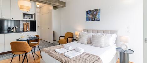 Une chambre d’hôtel moderne équipée d’un lit, d’un coin repas et d’une kitchenette.