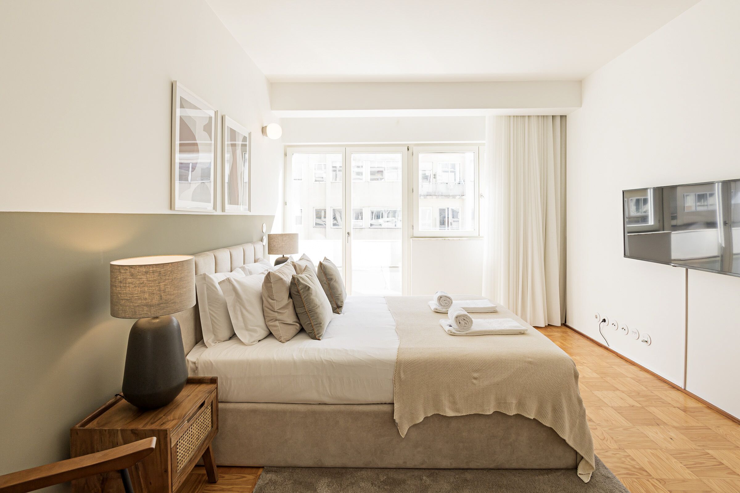 Une chambre à coucher avec un lit, une télévision, une lampe et une fenêtre avec des rideaux.