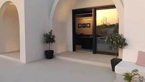 En moderne bygning med hvid facade, stor buegang og krukker med planter.