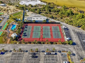 Un complejo de canchas deportivas con canchas de tenis, piscina y zona de estacionamiento.