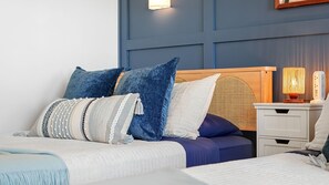 Un dormitorio con una cama, almohadas, una mesita de noche con lámpara y una lámpara de pared.