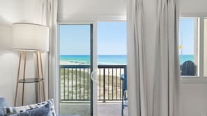 Ein Zimmer mit Blick auf den Strand, ein Balkon mit Geländer und eine Lampe.