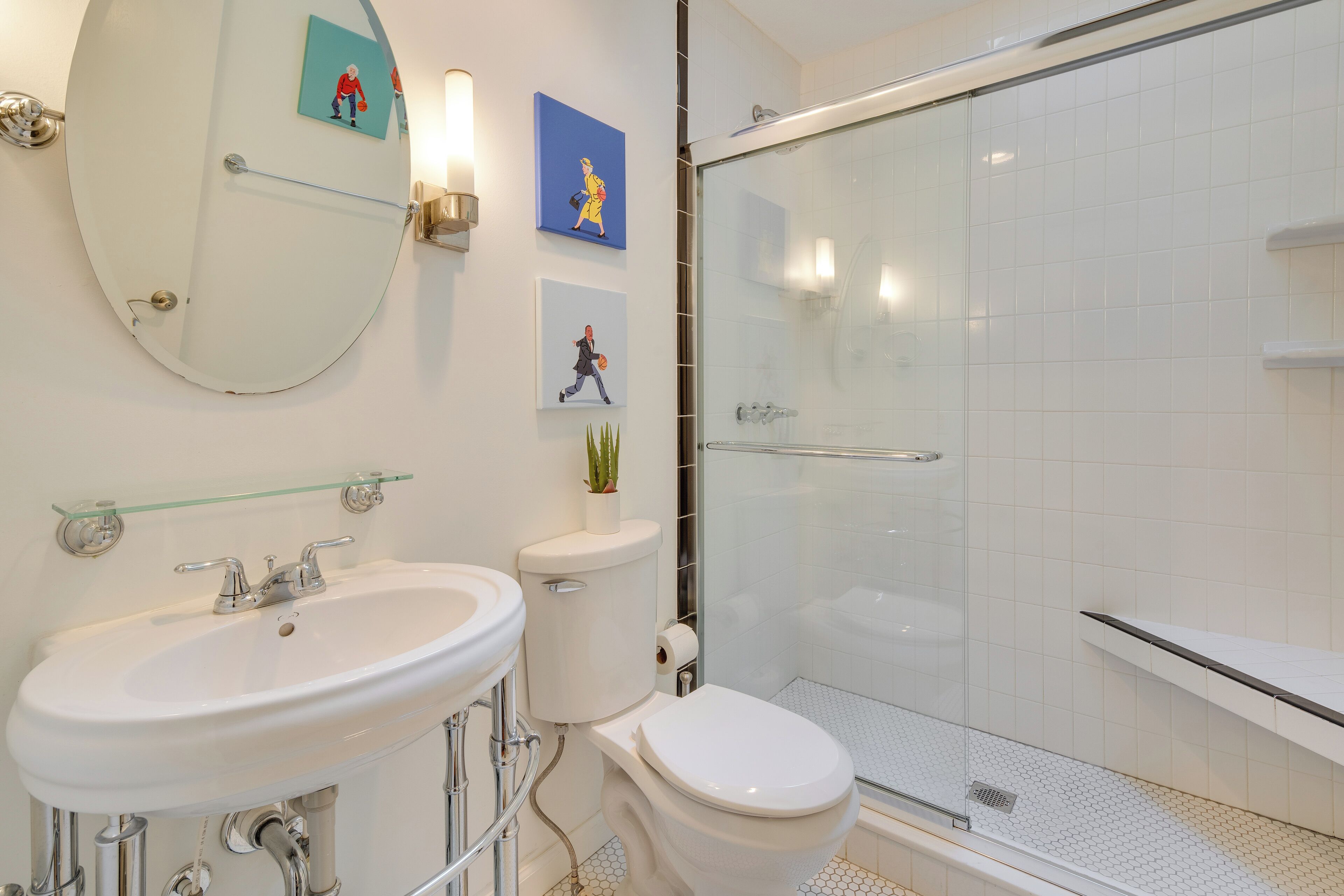 A bathroom with a white sink, toilet, and glass shower enclosure.