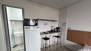 A compact room with a kitchenette, a bed, and a small bar area.