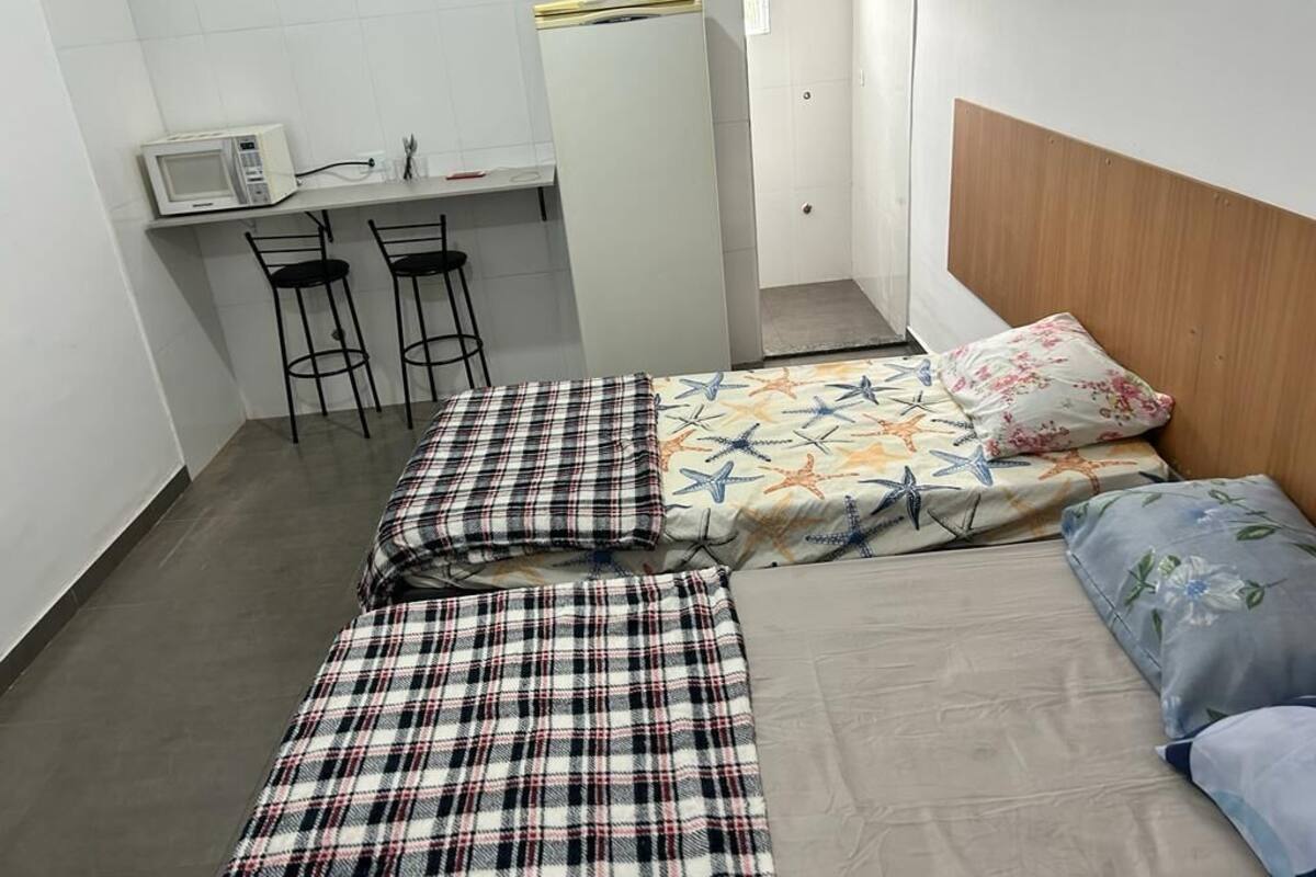 A small, compact room with a bed, a desk with a microwave, and two chairs.