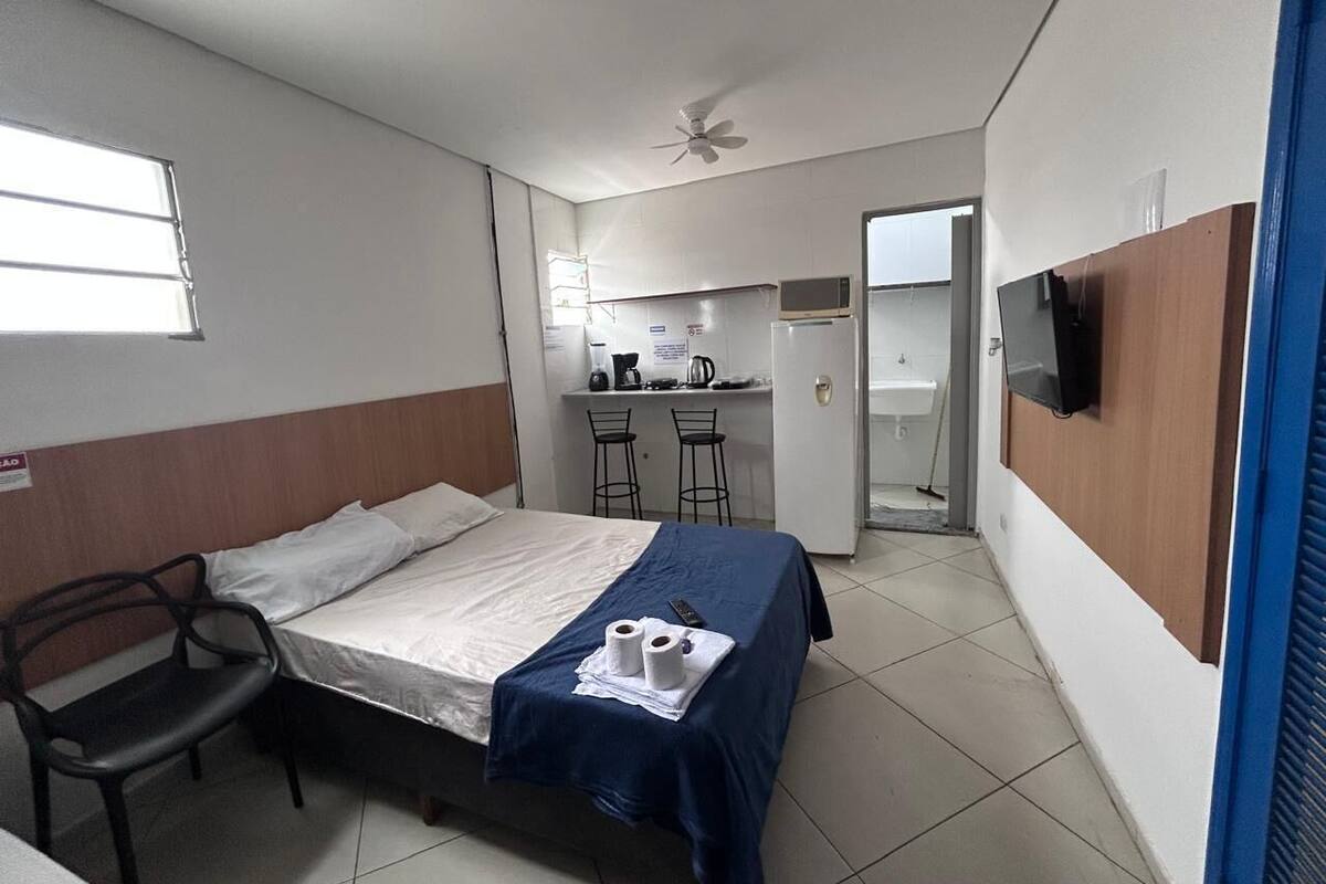 A compact hotel room with a single bed, a desk with two chairs, a microwave, and a television.