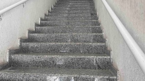 A staircase with granite steps and a handrail on both sides, leading to an upper floor.