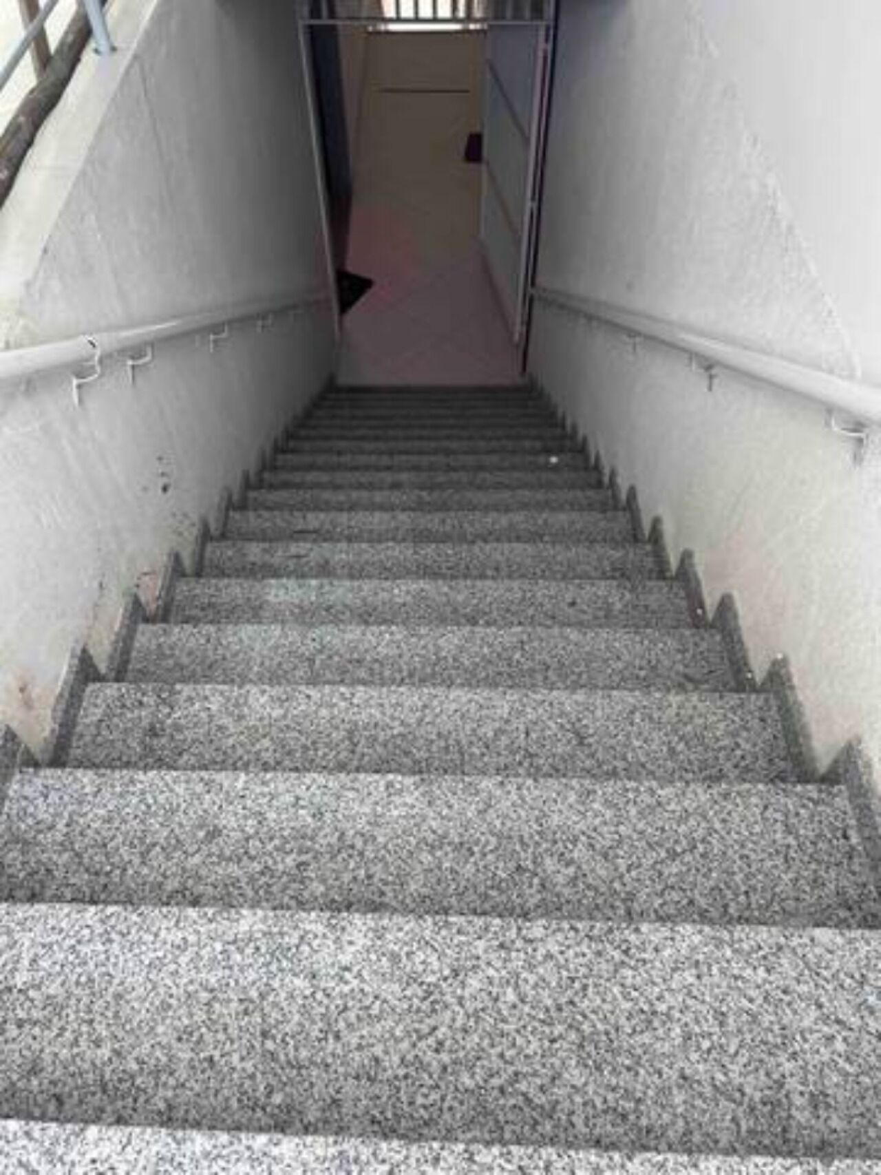 A concrete staircase with metal railings, leading to a door at the top.