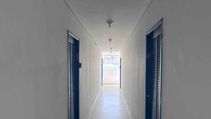 A corridor with tiled flooring and closed doors on both sides.
