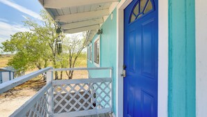 A blue door with a white porch and a lattice railing. - Pet-friendly Freeport Vacation Rental w/ Deck! (Freeport)