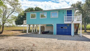 A two-story house with a blue garage door, a covered porch, and a small boat parked outside. - Pet-friendly Freeport Vacation Rental w/ Deck! (Freeport)
