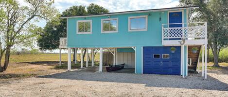 A two-story house with a blue garage door, a covered porch, and a small boat parked outside.