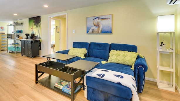 A living room with a blue sofa, a coffee table, and a painting of a bird on the wall. - Pet-friendly Freeport Vacation Rental w/ Deck! (Freeport)
