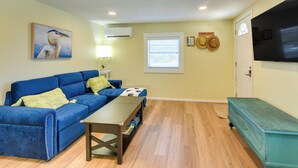 A living room with a blue sofa, a coffee table, a television, and a door with a sign. - Pet-friendly Freeport Vacation Rental w/ Deck! (Freeport)