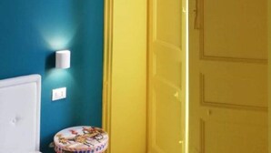 Una habitació amb parets color turquesa, una porta groga i una taula rodona petita amb un dibuix colorit.