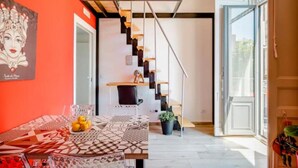 Un interior modern amb una escala, una zona de menjador amb estovell i una finestra gran.