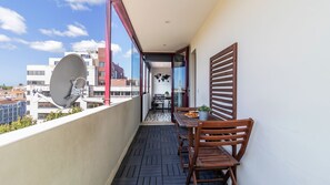 Un balcon avec une table et des chaises, une antenne parabolique et une vue sur les immeubles.