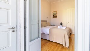 Une chambre à coucher avec un lit, un tableau accroché au mur et une porte donnant sur une autre pièce.